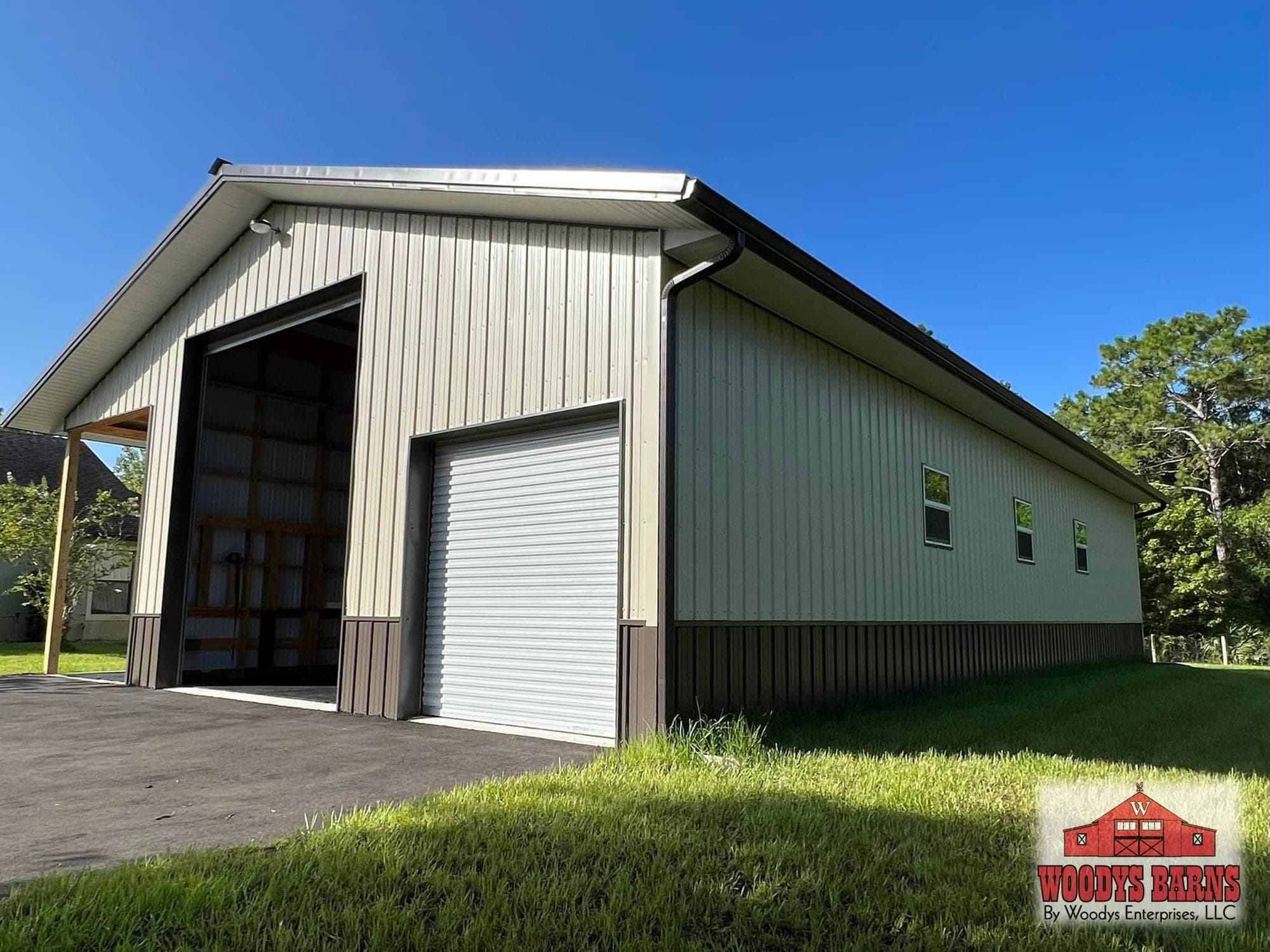 Enclosed storage building with a tan metal roll up door and green wainscot, built by Woodys Barns in Florida